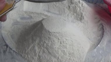 Çiftçinin eli un temizlemek için sepeti kullanıyor.