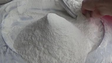 Çiftçinin eli un temizlemek için sepeti kullanıyor.