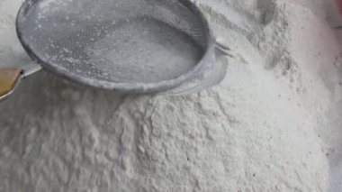 Çiftçinin eli un temizlemek için sepeti kullanıyor.