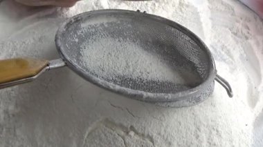 Çiftçinin eli un temizlemek için sepeti kullanıyor.