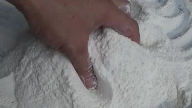 Çiftçinin eli un temizlemek için sepeti kullanıyor.