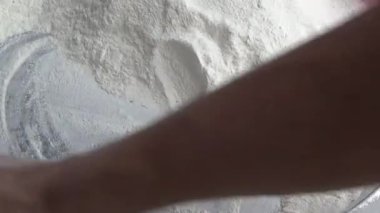 Çiftçinin eli un temizlemek için sepeti kullanıyor.