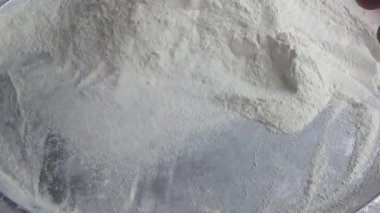 Çiftçinin eli un temizlemek için sepeti kullanıyor.