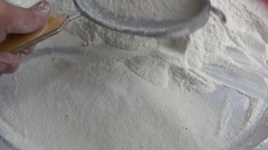 Çiftçinin eli un temizlemek için sepeti kullanıyor.