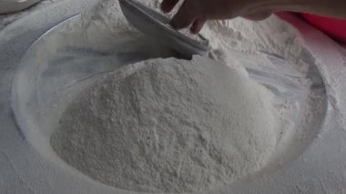 Çiftçinin eli un temizlemek için sepeti kullanıyor.