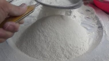 Çiftçinin eli un temizlemek için sepeti kullanıyor.