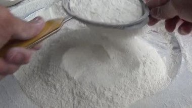 Çiftçinin eli un temizlemek için sepeti kullanıyor.