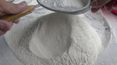 Çiftçinin eli un temizlemek için sepeti kullanıyor.