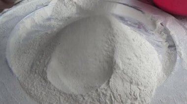 Çiftçinin eli un temizlemek için sepeti kullanıyor.