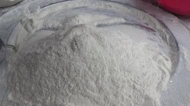 Çiftçinin eli un temizlemek için sepeti kullanıyor.