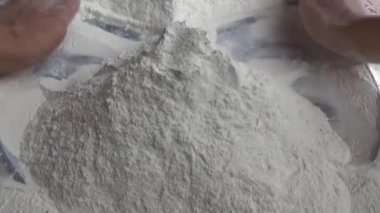 Çiftçinin eli un temizlemek için sepeti kullanıyor.