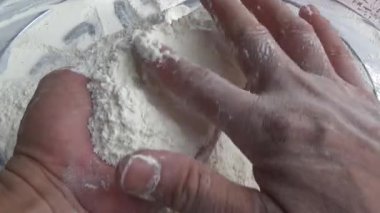 Çiftçinin eli un temizlemek için sepeti kullanıyor.