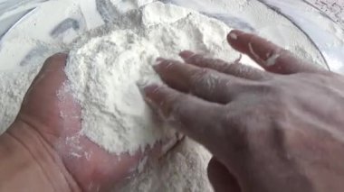 Çiftçinin eli un temizlemek için sepeti kullanıyor.