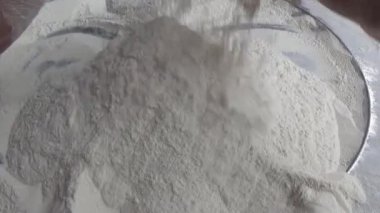 Çiftçinin eli un temizlemek için sepeti kullanıyor.