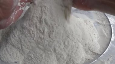 Çiftçinin eli un temizlemek için sepeti kullanıyor.