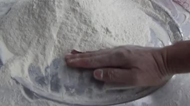 Çiftçinin eli un temizlemek için sepeti kullanıyor.