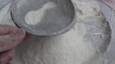 Çiftçinin eli un temizlemek için sepeti kullanıyor.