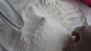 Çiftçinin eli un temizlemek için sepeti kullanıyor.