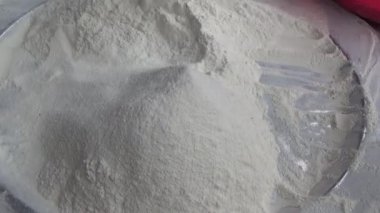 Çiftçinin eli un temizlemek için sepeti kullanıyor.