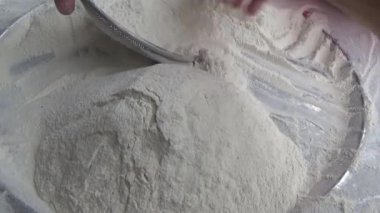 Çiftçinin eli un temizlemek için sepeti kullanıyor.