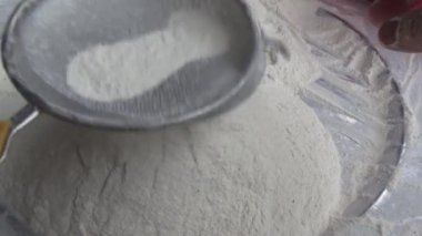 Çiftçinin eli un temizlemek için sepeti kullanıyor.