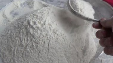 Çiftçinin eli un temizlemek için sepeti kullanıyor.