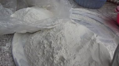 Çiftçinin eli un temizlemek için sepeti kullanıyor.