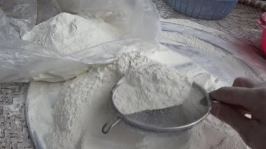 Çiftçinin eli un temizlemek için sepeti kullanıyor.