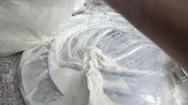 Çiftçinin eli un temizlemek için sepeti kullanıyor.