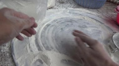 Çiftçinin eli un temizlemek için sepeti kullanıyor.