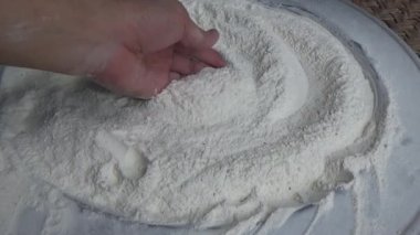 Çiftçinin eli un temizlemek için sepeti kullanıyor.