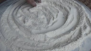 Çiftçinin eli un temizlemek için sepeti kullanıyor.