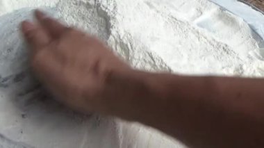 Çiftçinin eli un temizlemek için sepeti kullanıyor.