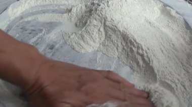 Çiftçinin eli un temizlemek için sepeti kullanıyor.