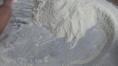 Çiftçinin eli un temizlemek için sepeti kullanıyor.