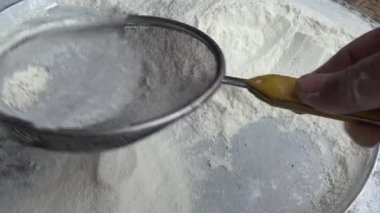 Çiftçinin eli un temizlemek için sepeti kullanıyor.