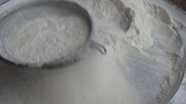 Çiftçinin eli un temizlemek için sepeti kullanıyor.