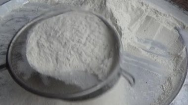 Çiftçinin eli un temizlemek için sepeti kullanıyor.