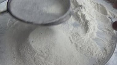 Çiftçinin eli un temizlemek için sepeti kullanıyor.