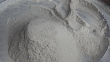 Çiftçinin eli un temizlemek için sepeti kullanıyor.