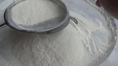 Çiftçinin eli un temizlemek için sepeti kullanıyor.