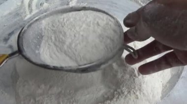 Çiftçinin eli un temizlemek için sepeti kullanıyor.