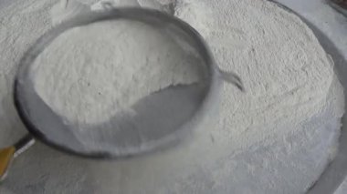 Çiftçinin eli un temizlemek için sepeti kullanıyor.