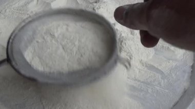 Çiftçinin eli un temizlemek için sepeti kullanıyor.