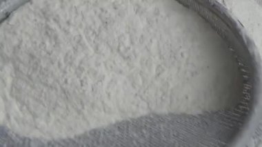 Çiftçinin eli un temizlemek için sepeti kullanıyor.