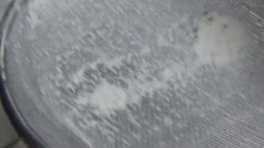 Çiftçinin eli un temizlemek için sepeti kullanıyor.