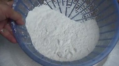 Çiftçinin eli un temizlemek için sepeti kullanıyor.