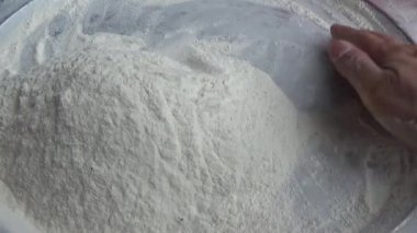 Çiftçinin eli un temizlemek için sepeti kullanıyor.