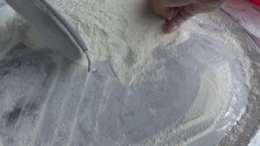 Çiftçinin eli un temizlemek için sepeti kullanıyor.