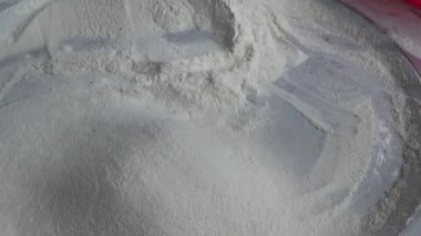 Çiftçinin eli un temizlemek için sepeti kullanıyor.